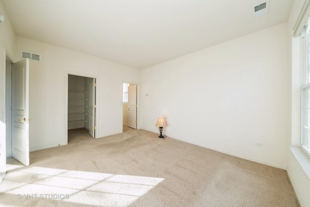 unfurnished bedroom with light carpet, a walk in closet, and a closet