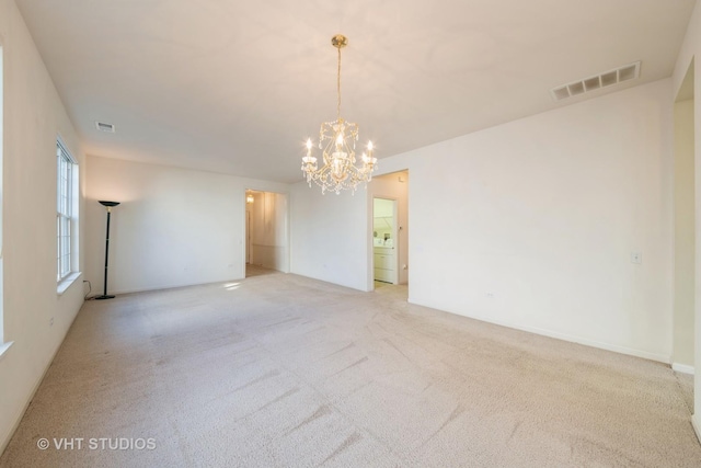 spare room with light carpet and an inviting chandelier