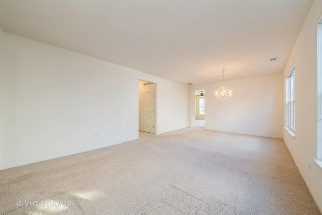 unfurnished room featuring light colored carpet and a chandelier