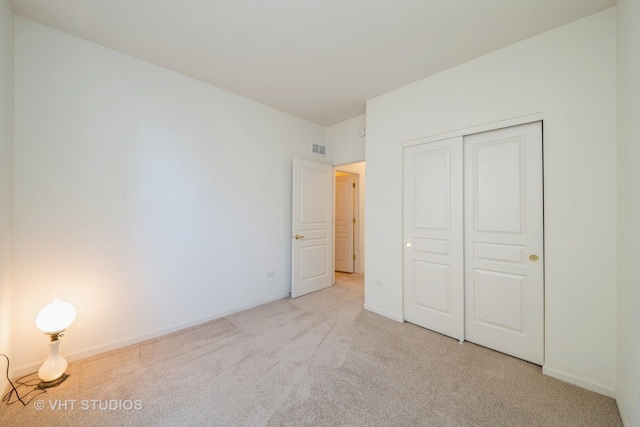 unfurnished bedroom with light colored carpet and a closet