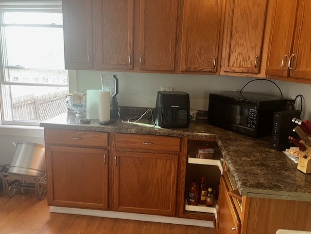 kitchen with dark stone counters, plenty of natural light, and light hardwood / wood-style floors