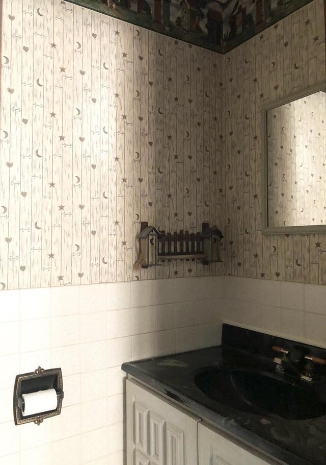 bathroom featuring vanity and wallpapered walls