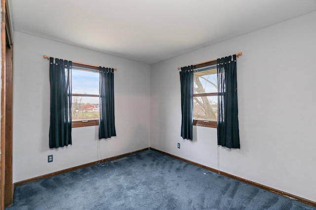 empty room featuring dark carpet and baseboards