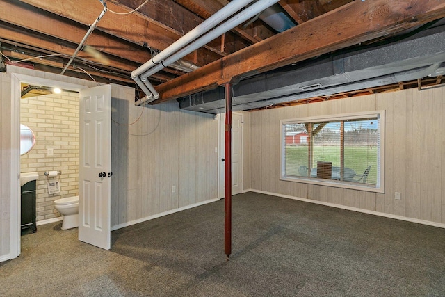 below grade area featuring carpet flooring, wooden walls, and baseboards