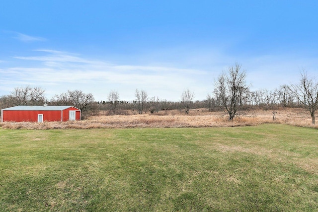 view of yard featuring a garage, an outbuilding, a rural view, and driveway