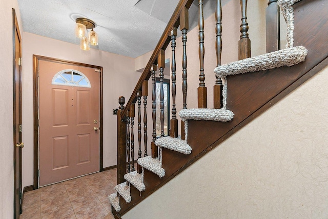 foyer featuring stairs, a textured ceiling, and tile patterned floors