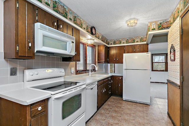 kitchen featuring white appliances, a textured ceiling, a wealth of natural light, and a sink