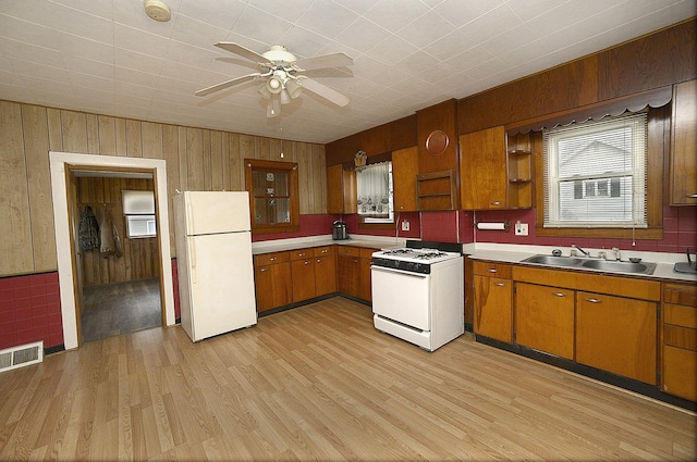 kitchen featuring ceiling fan, sink, light hardwood / wood-style flooring, wood walls, and white appliances