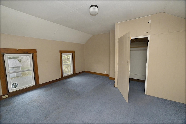 additional living space with dark colored carpet and lofted ceiling