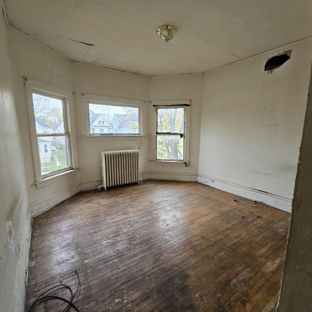 empty room with radiator heating unit and dark hardwood / wood-style floors