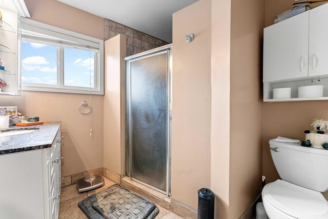 bathroom with tile patterned floors, a shower with door, vanity, and toilet