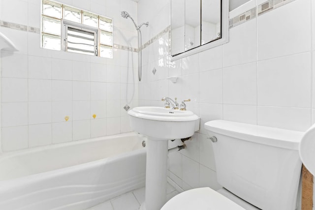 bathroom with tiled shower / bath combo, toilet, and tile walls