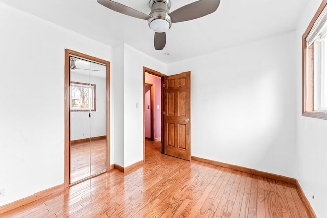 unfurnished bedroom featuring ceiling fan, light hardwood / wood-style flooring, multiple windows, and a closet