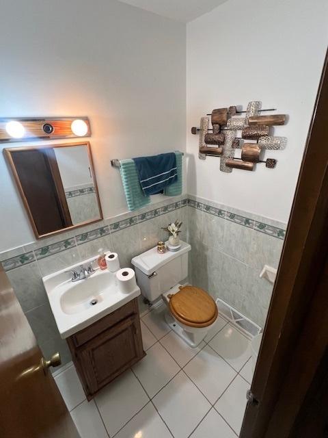 bathroom featuring vanity, tile walls, tile patterned floors, and toilet