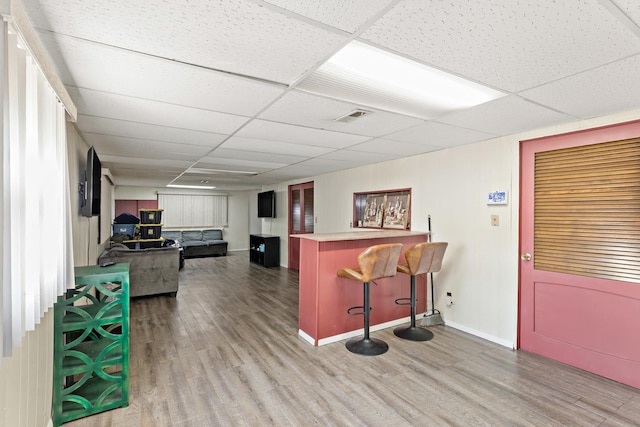 bar with a drop ceiling and hardwood / wood-style floors