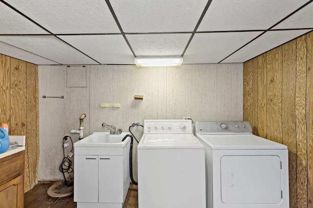 laundry area featuring sink, washing machine and clothes dryer, and wood walls