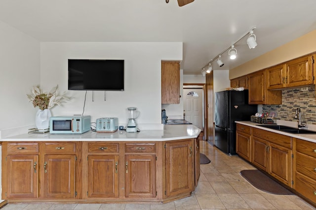 kitchen with sink, backsplash, light tile patterned floors, and black fridge