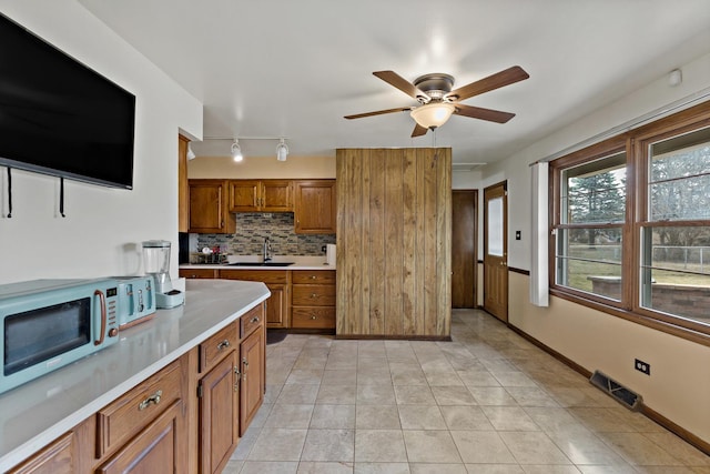 kitchen with tasteful backsplash, sink, ceiling fan, and light tile patterned flooring