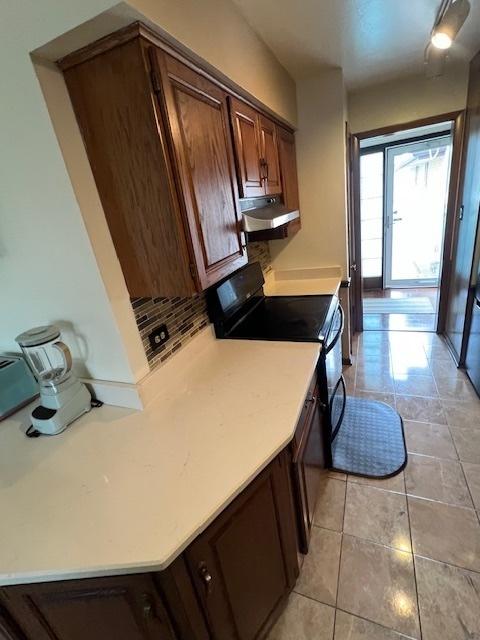 kitchen featuring black / electric stove, tasteful backsplash, and light tile patterned floors