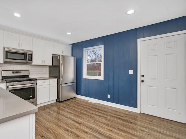 kitchen featuring hardwood / wood-style flooring, white cabinets, stainless steel appliances, and tasteful backsplash