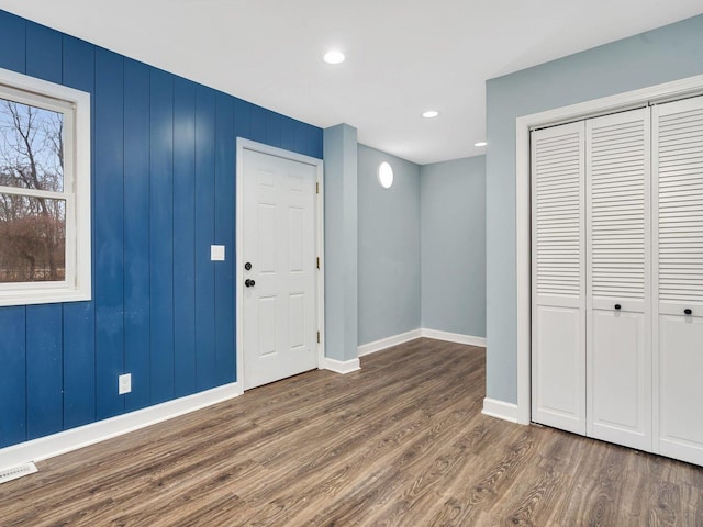 entrance foyer featuring dark hardwood / wood-style flooring and wooden walls