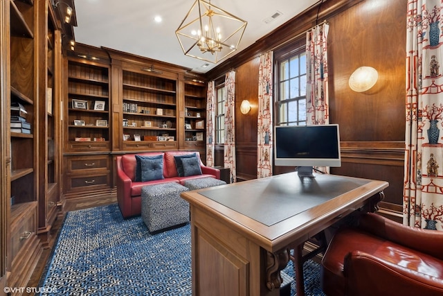 office space with an inviting chandelier, dark hardwood / wood-style flooring, built in features, wooden walls, and ornamental molding