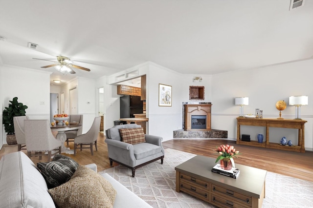 living room with crown molding, light hardwood / wood-style flooring, and ceiling fan