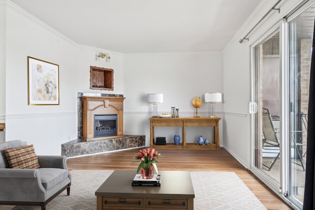 living room featuring crown molding, a high end fireplace, and light hardwood / wood-style floors