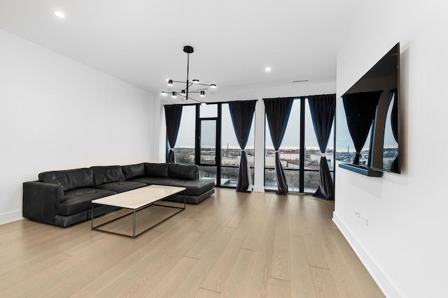 living room with light hardwood / wood-style floors, an inviting chandelier, and expansive windows