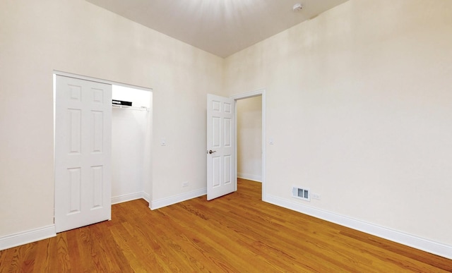 unfurnished bedroom featuring a closet, a high ceiling, and light wood-type flooring