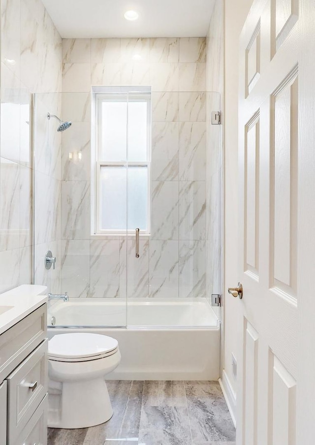 full bathroom featuring vanity, toilet, and bath / shower combo with glass door