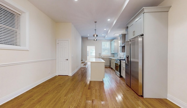 kitchen with stainless steel appliances, light hardwood / wood-style flooring, a center island, white cabinetry, and hanging light fixtures