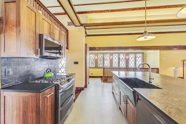 kitchen with baseboards, decorative backsplash, appliances with stainless steel finishes, a sink, and beam ceiling