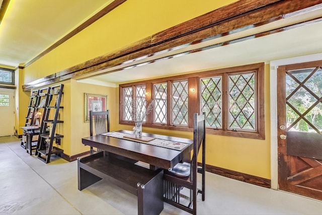 dining room featuring baseboards, plenty of natural light, ornamental molding, and concrete flooring