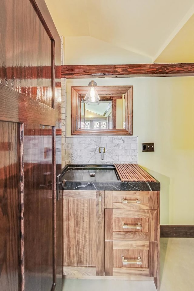 bar with tasteful backsplash, vaulted ceiling, and baseboards