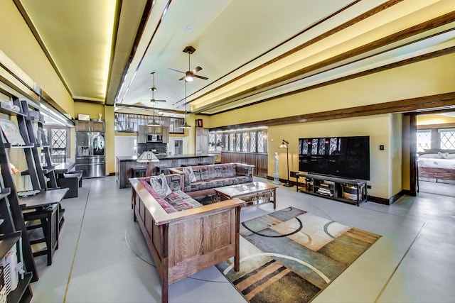 living area featuring concrete flooring, a ceiling fan, and baseboards