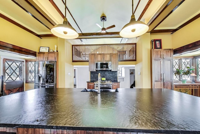 kitchen with appliances with stainless steel finishes, beamed ceiling, dark countertops, and a sink