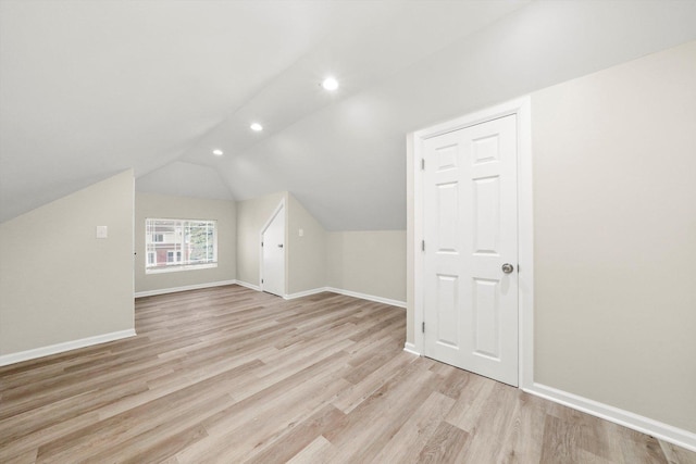 additional living space with light hardwood / wood-style floors and vaulted ceiling