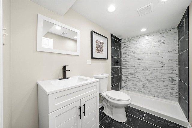 bathroom with vanity, toilet, and tiled shower