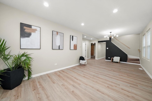 unfurnished living room with a notable chandelier and light wood-type flooring