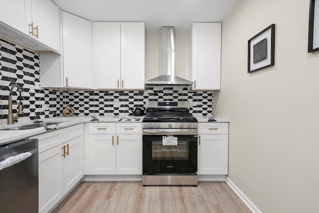 kitchen featuring wall chimney exhaust hood, dishwasher, white cabinetry, and gas range