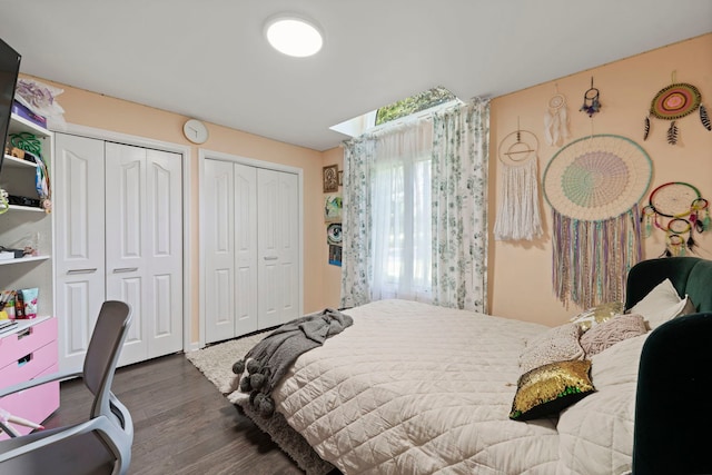 bedroom with dark hardwood / wood-style floors and multiple closets