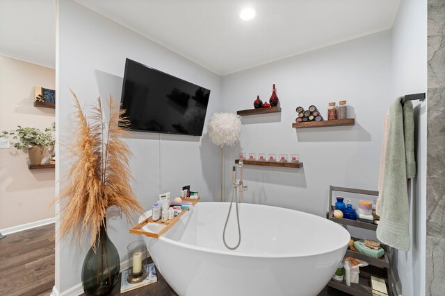 bathroom featuring a bath, ornamental molding, and wood-type flooring