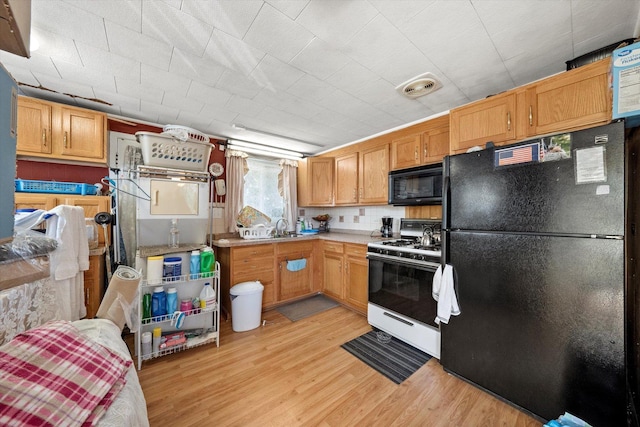 kitchen with sink, light hardwood / wood-style floors, and black appliances