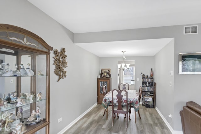 dining space featuring light hardwood / wood-style flooring and an inviting chandelier