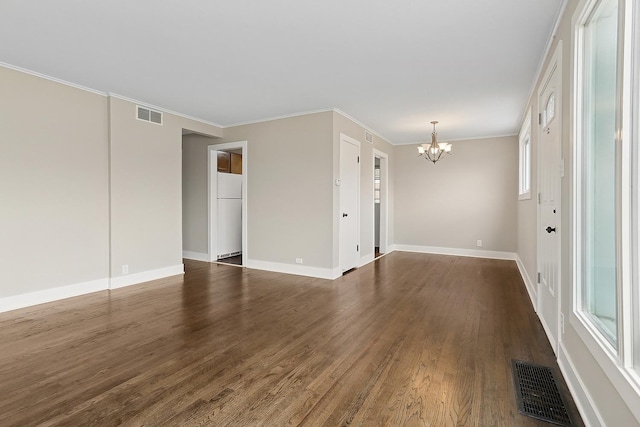 empty room featuring a chandelier, ornamental molding, a wealth of natural light, and dark wood-type flooring