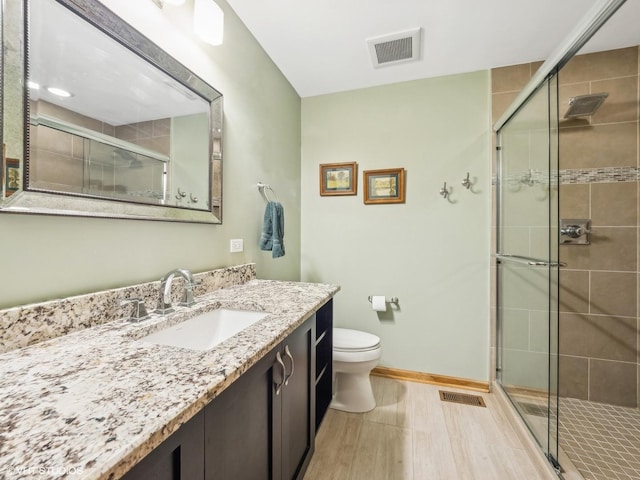 bathroom featuring vanity, toilet, a shower with door, and wood-type flooring