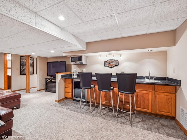 bar with carpet flooring, sink, and a drop ceiling