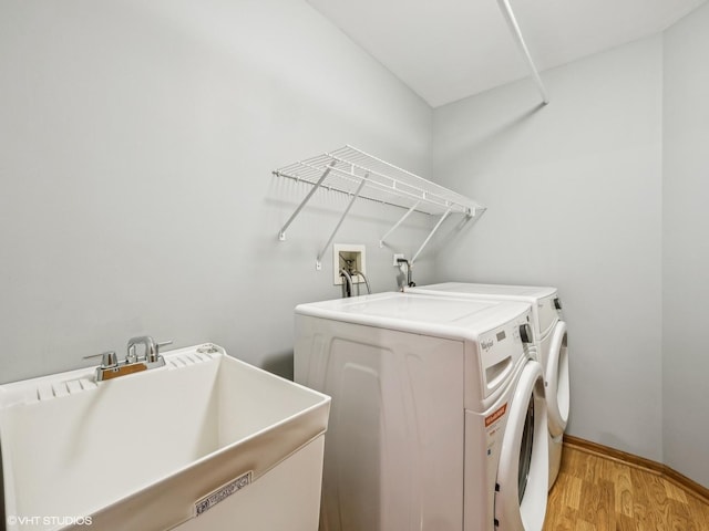 washroom featuring washing machine and clothes dryer, light wood-type flooring, and sink