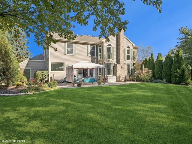 rear view of property featuring a gazebo, a patio area, and a yard